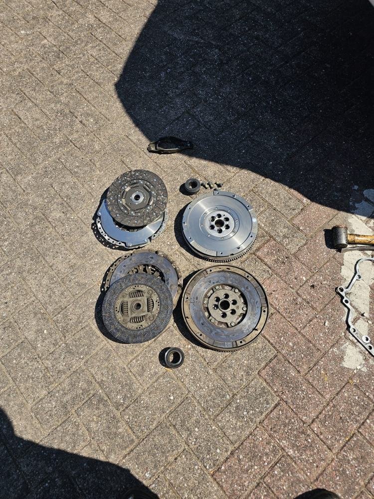 Clutch and flywheel parts laid out on a paved drive