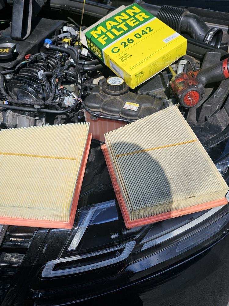 New and used air filters laid across an engine bay