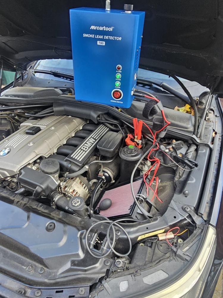 A smoke leak detector connected to an engine bay