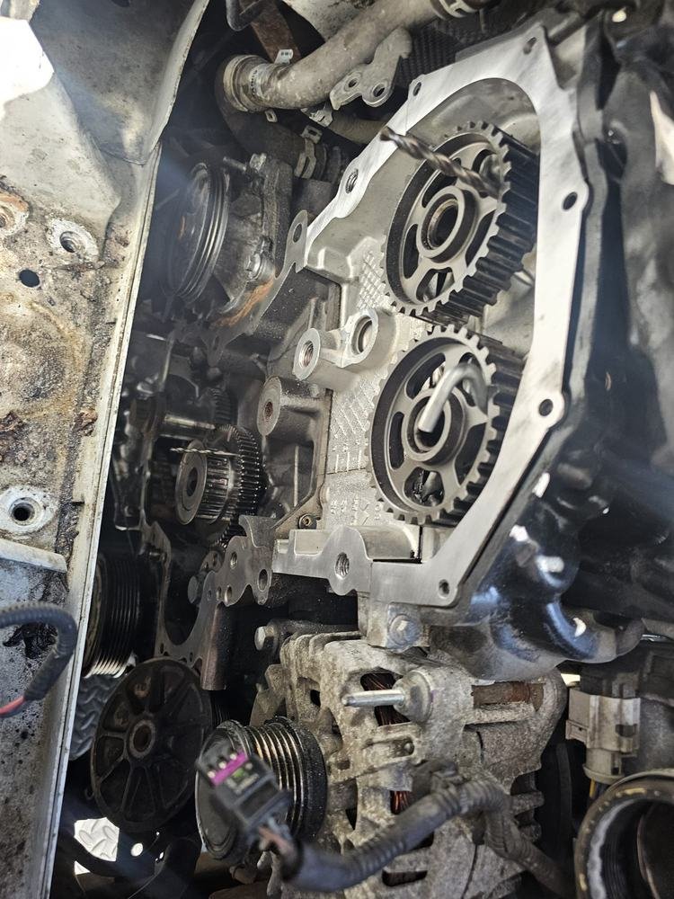 An engine with its wet belt and cam sprockets exposed during a belt replacement